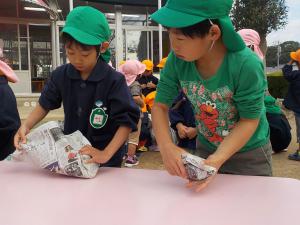 子供たちがいもを新聞紙で覆っています。