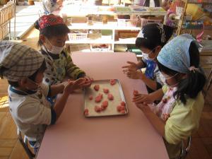 桃色の団子を丸める5歳児