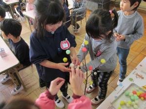 赤芽の木に団子を飾る4歳児
