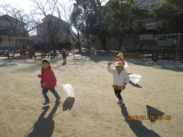 戸外でたこ揚げをしている２歳児