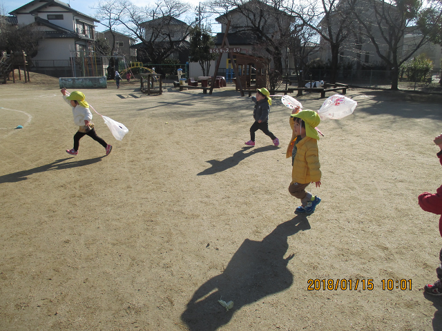 戸外でたこ揚げを楽しんでいる２歳児