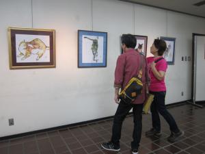 猫の作品を見ている内藤勲さん（似顔絵師）です。