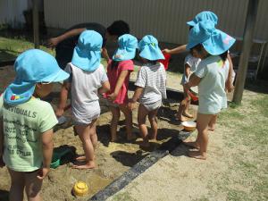砂場で池を作る子の画像