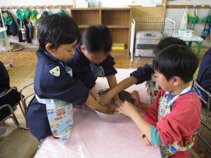 5歳児4人が力を合わせて餅粉を混ぜている様子