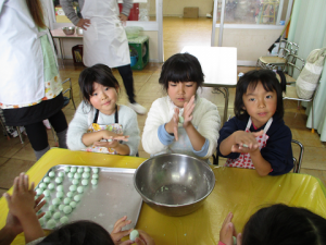 5歳児女児たちが緑色の団子を丸めている様子