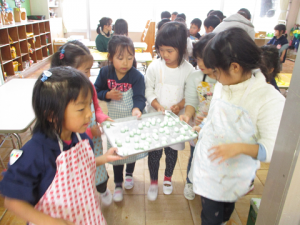 5歳児の子どもたちが完成した団子を配膳室まで運んでいる様子