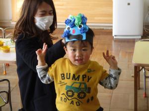 できたお面を被ってポーズをする2歳児