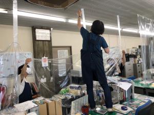 この写真は事務室の飛沫防止カーテンを手直ししているところです。