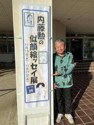 この写真は展示の看板と内藤勲さんです。