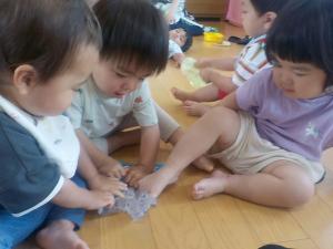 手や足でスライムを触る１歳児