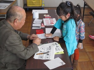 子どもの部の様子（はんこを紙に押しています）。