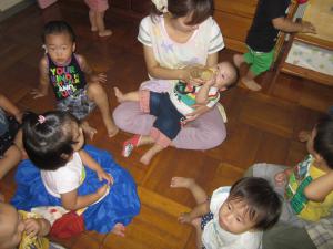 ミルクを飲む0歳児を見つめる子ども達